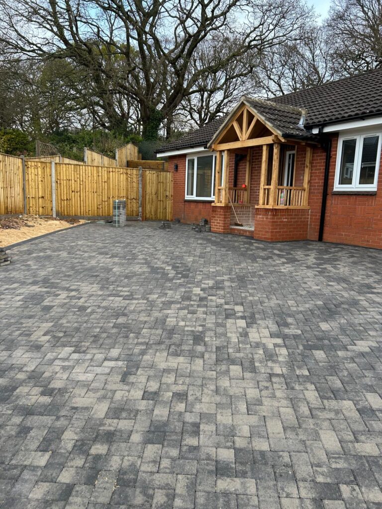 This image collage showcases a residential driveway and garden. A large, paved patio made of interlocking grey and light-grey paving stones is the central focus. It sits in front of a red brick house featuring a new wooden porch with a gabled roof.