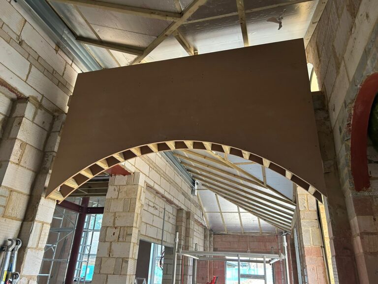 Key alternative text options, ranked by suitability:

1.  **Concise & Descriptive (Recommended):**
    > Construction view of a new wooden-framed arched entrance under a glass roof in a stone building.

2.